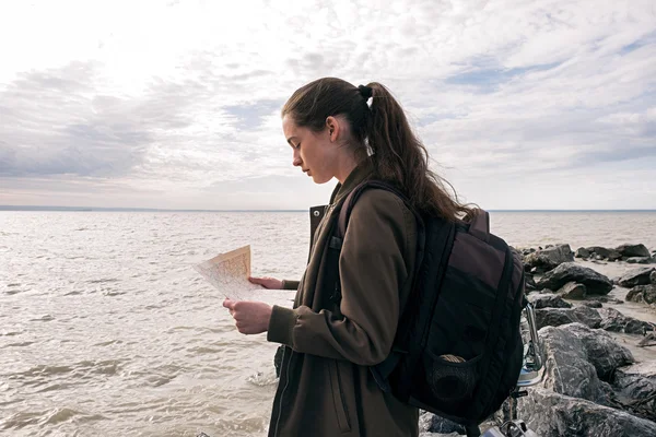 Side view of brunette traveler with backpack and map