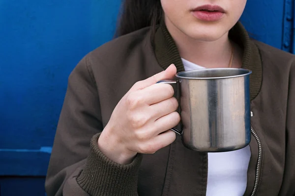 Close-up of girl holding metal traveling cup with drink