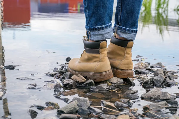 Waterproof trekking boots on rocks at water