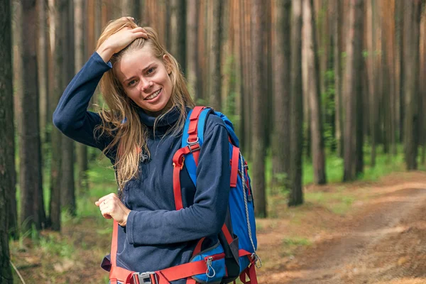 Young and pretty backpacker touching hair and smiling away