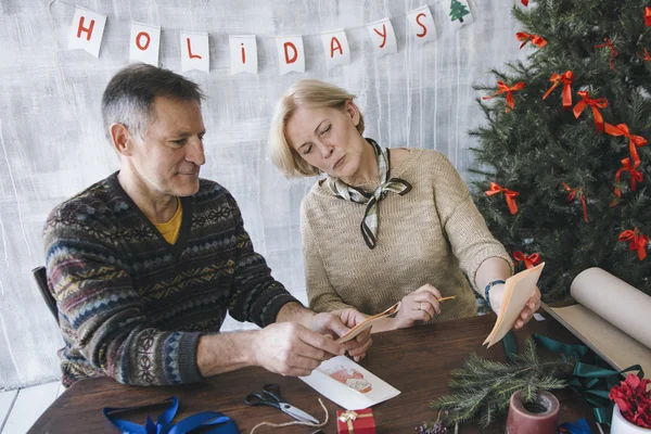 Two elderly people looking at their Christmas cards