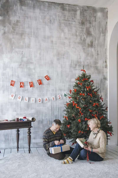 Couple of elderly man and woman opening Christmas presents