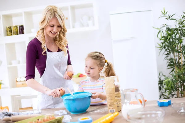 Mother teaching child how to make dough