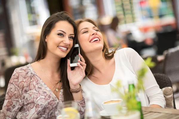 Young friends laughing while drinking coffee