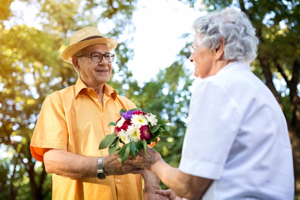 Couple in love with bouquet, senior man giving flowers to his lo