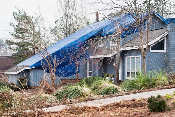 Wood Frame House with Tarpaulin Covering Roof After a Tornado