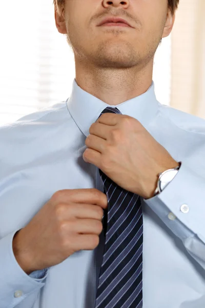 Handsome businessman preparing to official event, straighten tie