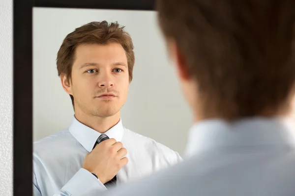 Handsome businessman preparing to official event, straighten tie