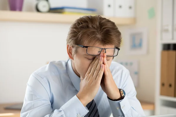 Tired office worker touching his bridge of nose to give rest to