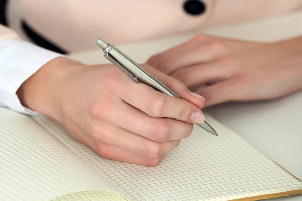 Woman hand holding silver pen ready to make note in opened noteb