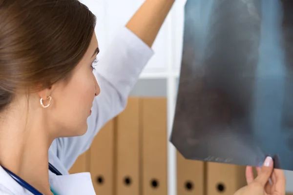 Young female medical doctor or intern looking at lungs x-ray ima