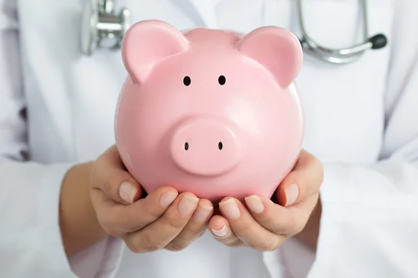 Female Doctor Holding Piggy Bank