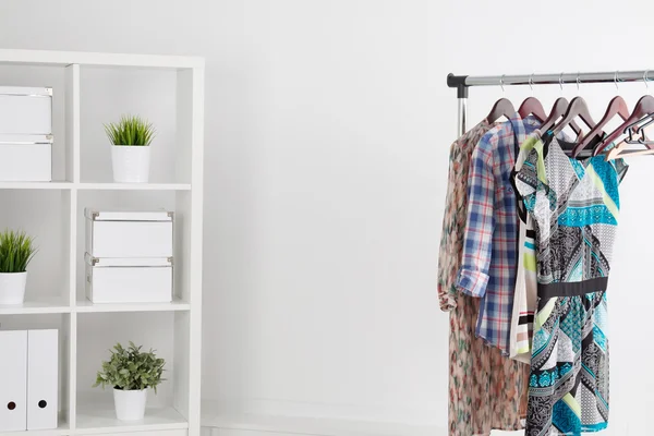Colorful clothes on hanger in white room