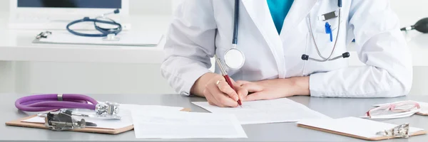 Female medical doctor writing something sitting at her office