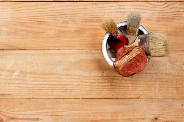 Paint brushes in a metal pot on wooden boards