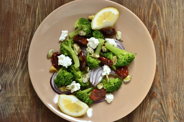 Salad with broccoli, dried tomatoes, feta, onions and pumpkin seeds