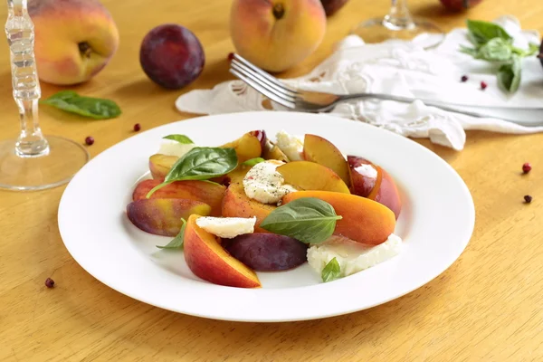 Salad with peaches, goat cheese, plum and basil