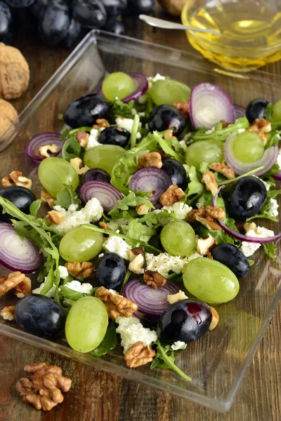 Salad with various grapes, goat cheese, purple onion, arugula and walnuts
