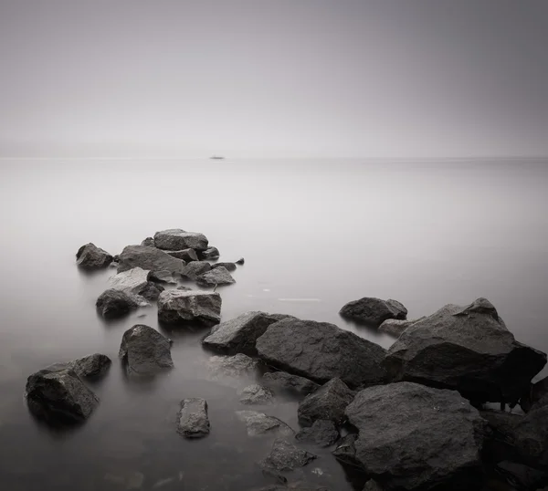 Minimal long exposure coastal landscape with stones and water