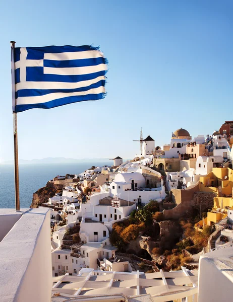 Oia, Santorini. Windmill on cliff side, and Greek flag.