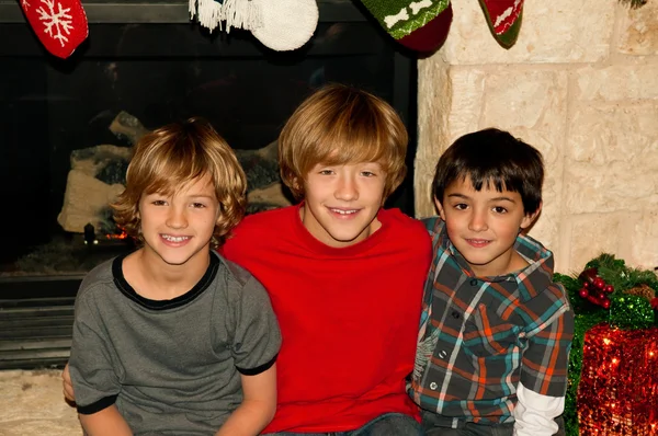 Portrait of three boys sitting on fireplace at Christmas.
