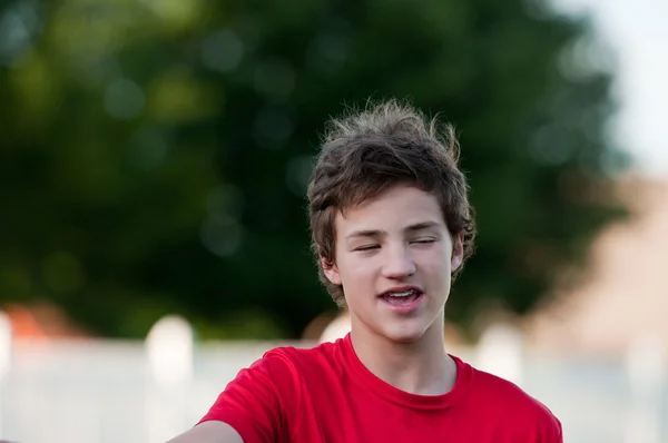 Handsome teenage boy outdoors with braces and messy hair with ey