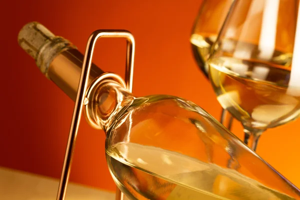 White wine bottle on a metal wine rack and two glasses with white wine