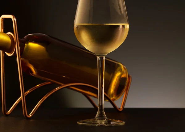 Glass of white wine and white wine bottle  on a metal wine rack