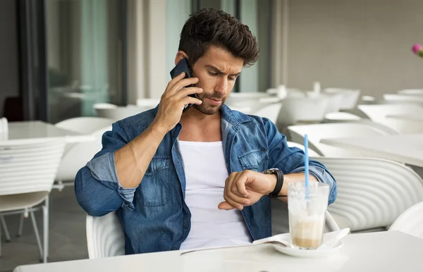 Young handsome man calling and checking the time