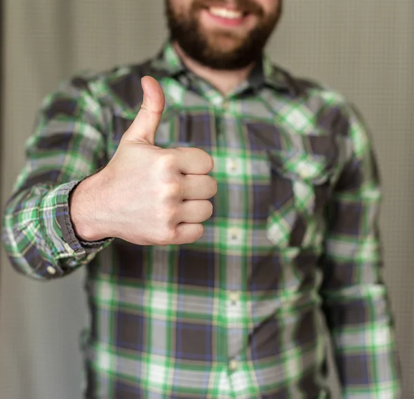 Smiling, bearded man in a checkered shirt did a thumbs-up