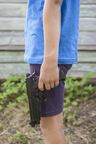 Boy holds in its hands of the gun the background an old wooden a