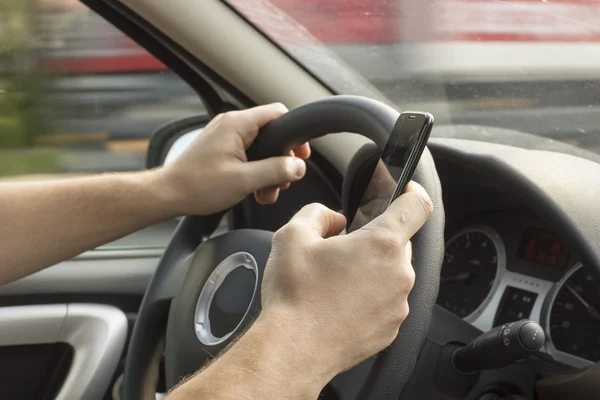 Man is driving a car and holding a mobile phone