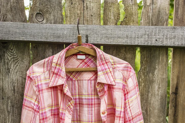 Shirt hangs a on hanger on the old fence from boards in a villag