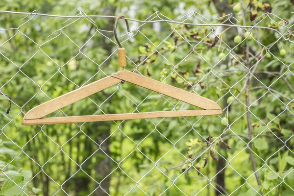 Metal hangers hanging on a metal fence on a background of greens