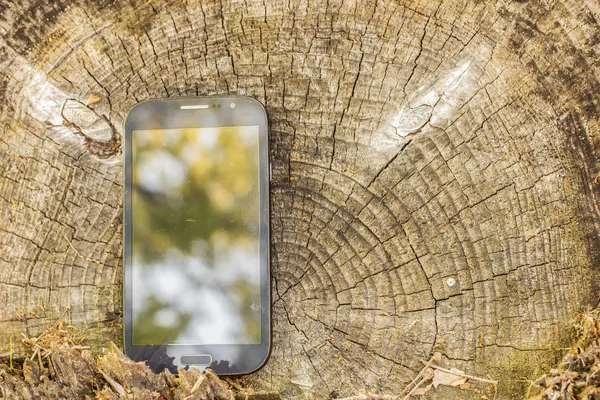 Mobile phone lies on the old a tree stump in a village