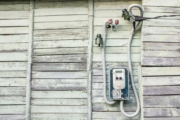 Modern electrical meter hanging on the old wooden house outdoors