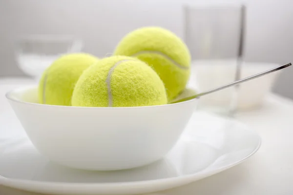 Tennis balls are in a bowl instead of ice cream. White variant.