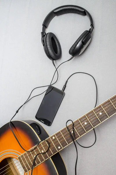 Guitar, headphones, silhouette of a guitarist playing and mobile phone