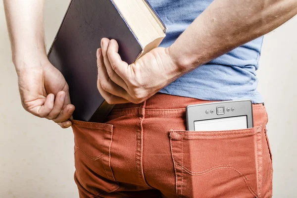 In the back pocket of jeans is an e-book, a man tries to shove in a second pocket paper book