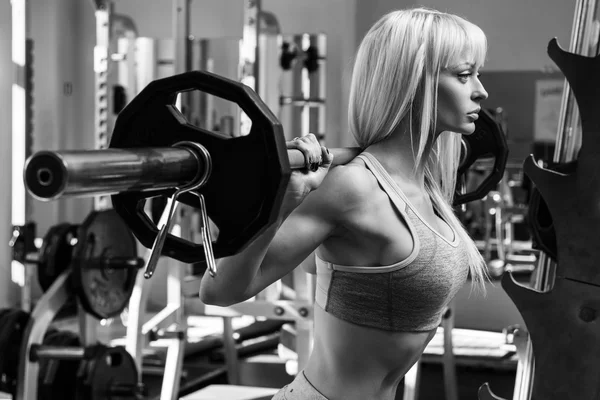 Beautiful woman with barbell on her shoulders