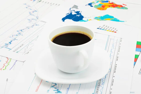 Coffee cup over world map and some financial documentation - close up studio shot