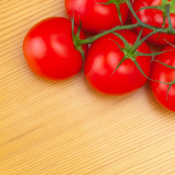 Few red tomatoes on wooden table - view from top