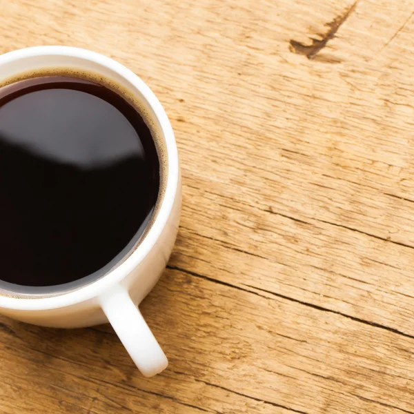 Coffee in white ceramic cup on wooden table - view from top - 1 to 1 ratio