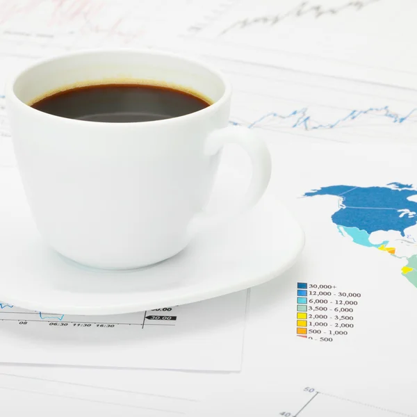 Coffee cup over world map and financial documents - 1 to 1 ratio