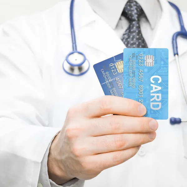 Doctor holding two credit cards in his hand - health care concept