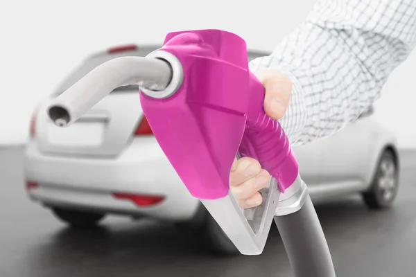 Pink color fuel pump gun in hand with car on background