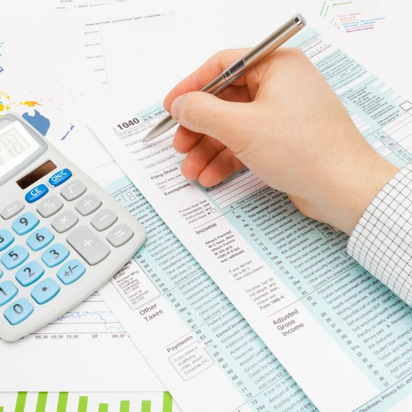 Male filling out 1040 US Tax Form using silver ball pen - studio shot