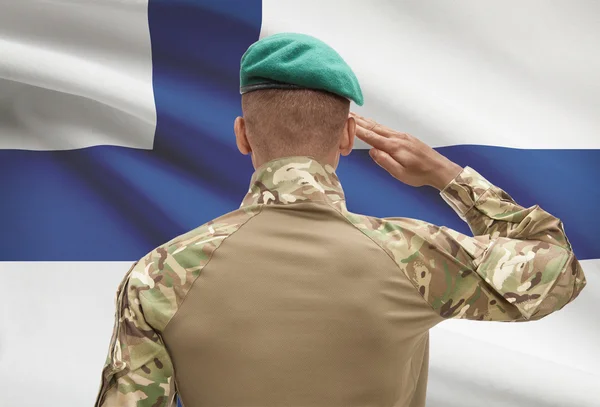 Dark-skinned soldier with flag on background - Finland