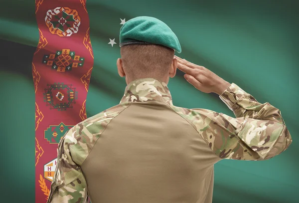 Dark-skinned soldier with flag on background - Turkmenistan