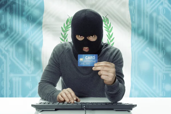 Dark-skinned hacker with flag on background holding credit card - Guatemala